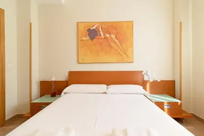 a bedroom with a white bed and a painting on the wall at Global Vacacional, Apartamento con gran terraza en la playa de Puerto Sagunto in Puerto de Sagunto