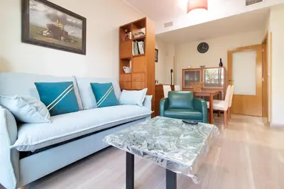 a living room with a blue couch and a table at Global Vacacional, Apartamento con gran terraza en la playa de Puerto Sagunto in Puerto de Sagunto