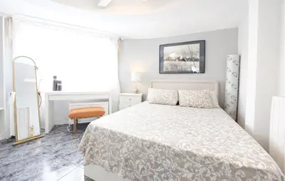 a white bedroom with a bed and a chair at Marisol Molina in Sueca