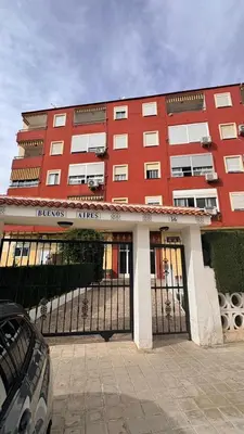 a red building with a gate in front of it at Apartamento con piscina, playa y cerca de Valencia in Puebla de Farnals