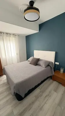a bedroom with a large bed with a blue wall at Apartamento con piscina, playa y cerca de Valencia in Puebla de Farnals