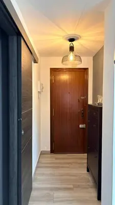 a hallway with a wooden door and a room with a table at Apartamento con piscina, playa y cerca de Valencia in Puebla de Farnals