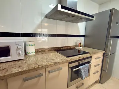 a kitchen with a stove top oven next to a microwave at Reinapart Patacona Beach Sunrise in Valencia