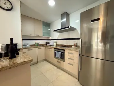 a kitchen with a stainless steel refrigerator and a clock at Reinapart Patacona Beach Sunrise in Valencia