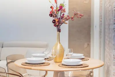 a table with plates and a vase with flowers at GMG Apartments & Suites in Valencia