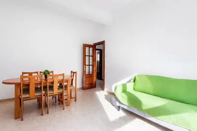 a living room with a table and a green couch at Guest Ready - Bright flat well‑located urban stay in Valencia