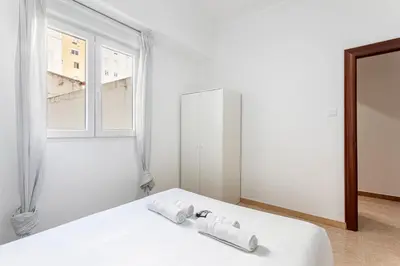 a white bedroom with a bed and a window at Guest Ready - Bright flat well‑located urban stay in Valencia