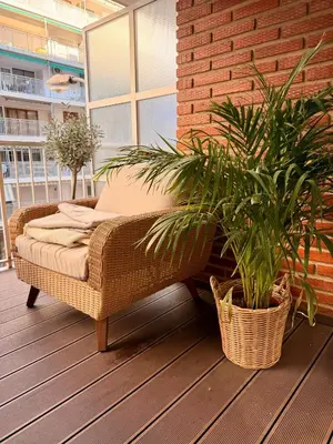 a wicker chair sitting on a porch with two plants at Sunny Waves Apartment in Cullera