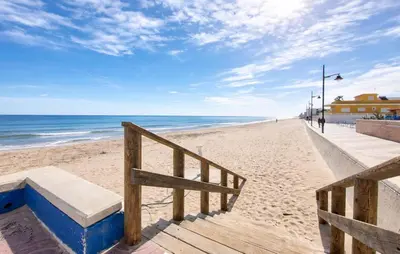 a sandy beach with a wooden staircase and the ocean at 4 Bedroom Stunning Home In Sueca in Sueca