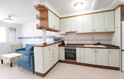 a kitchen with white cabinets and a blue couch at 4 Bedroom Stunning Home In Sueca in Sueca