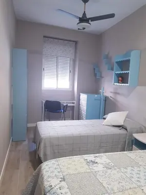 a bedroom with two beds and a table and a chair at Cabañal Flat, Wi-Fi & AACC in Valencia