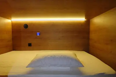a bedroom with a white bed with a wooden wall at Joaquin Sorolla Pod Hostel in Valencia