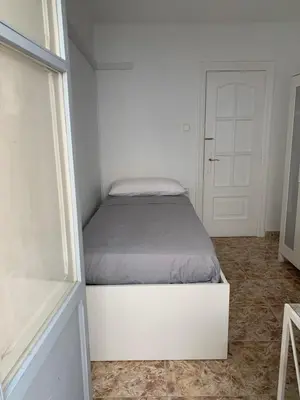 a white bed in a white room with a window at Habitacion individual cerca del puerto in Valencia