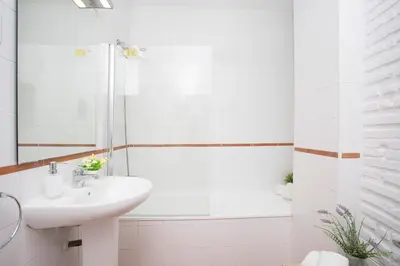 a white bathroom with a sink and a bath tub at SingularStays Botanico29 in Valencia