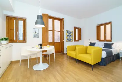 a bedroom with a bed and a table and yellow chairs at Valencia Home Carmen in Valencia