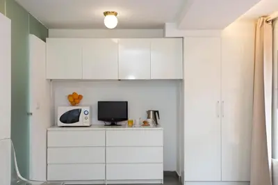 a small kitchen with white cabinets and a microwave at SingularStays Botanico 29 Rooms in Valencia