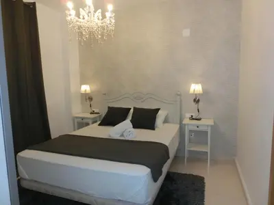 a bedroom with a white bed with two tables and a chandelier at Total Valencia Old City Luxury in Valencia