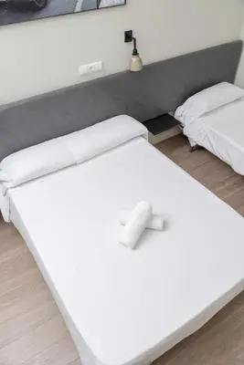 two beds in a room with white sheets at NWT Central Station Valencia in Valencia
