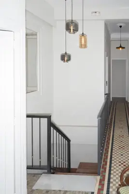 a hallway with white walls and a staircase with pendant lights at NWT Central Station Valencia in Valencia
