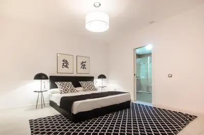 a white bedroom with a bed and a black rug at Valencia Luxury - Boutique Center in Valencia