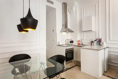 a kitchen with a glass table and two black chairs at Baron Suites Reina in Valencia