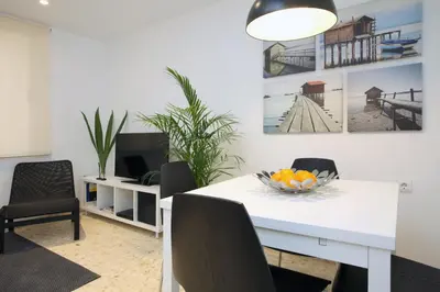 a dining room with a white table with chairs and a bowl of fruit at Poeta Llombart Apartment in Valencia