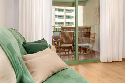 a living room with a green couch and a table at ApartUP Patacona Beach I in Valencia