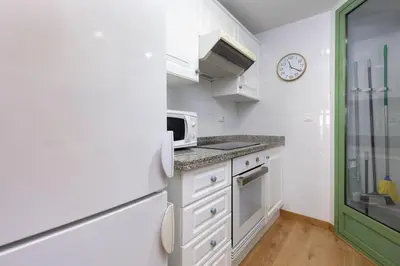a kitchen with white cabinets and a clock on the wall at ApartUP Patacona Beach I in Valencia