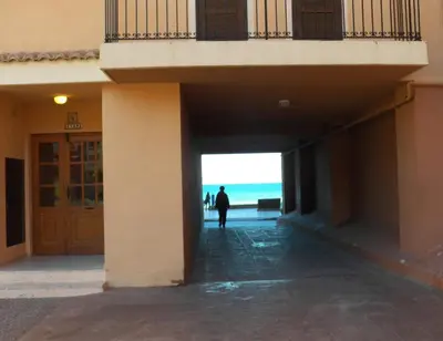 a man walking into a building with the ocean in the background at Valencia Port Saplaya in Port Saplaya