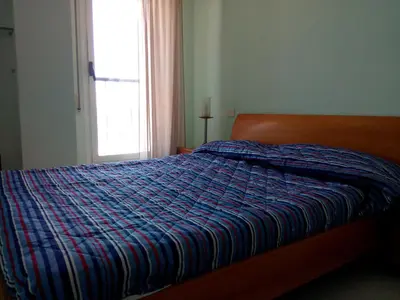 a bedroom with a bed with a blue comforter and a window at Valencia Port Saplaya in Port Saplaya