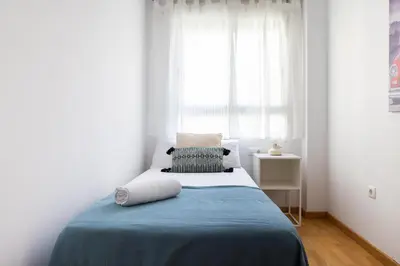 a bedroom with a bed with a blue blanket and a window at Medinaceli airco, wifi and free parking in Valencia