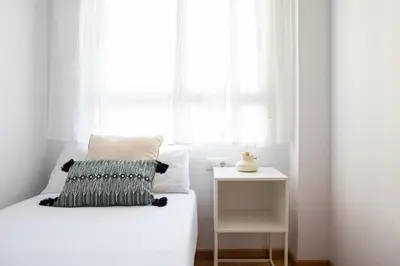 a white bedroom with a bed and a window at Medinaceli airco, wifi and free parking in Valencia