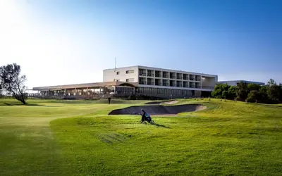 a person on a golf course with a building in the background at Parador de El Saler in El Saler