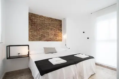a bedroom with a bed with a brick wall at Apartamentos Marina Playa in Valencia