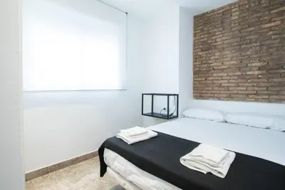 a bedroom with a bed with a brick wall at Apartamentos Marina Playa in Valencia