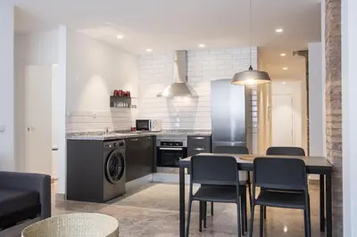 a kitchen with a table and chairs and a dishwasher at Apartamentos Marina Playa in Valencia