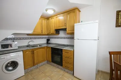 a kitchen with wooden cabinets and a white refrigerator at Casa rural Vista Alegre , cerca de Valencia y Castellón in Caudiel