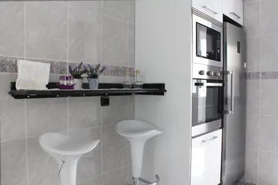 a kitchen with a white stool and a microwave at Sweet Caroline Apartment in Valencia