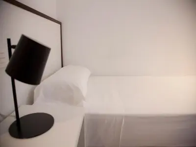 a bedroom with a white bed with a black lamp at Flats Friends Soho Suites in Valencia