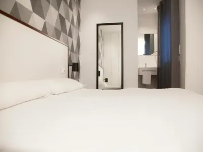 a bedroom with a large white bed and a bathroom at Flats Friends Soho Suites in Valencia