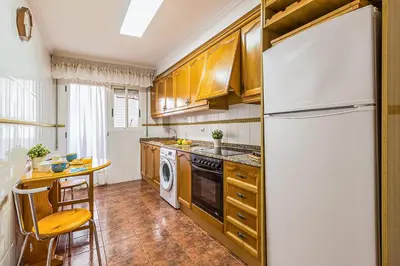 a kitchen with wooden cabinets and a white refrigerator at MoYma Playa in Puerto de Sagunto
