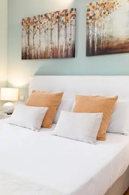 a bedroom with a white bed with two paintings on the wall at Travel Habitat Torres de Serrano in Valencia