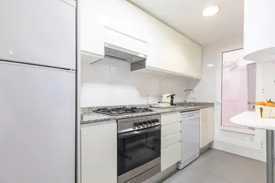 a white kitchen with a stove and a refrigerator at Travel Habitat Torres de Serrano in Valencia