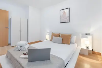 a bedroom with a white bed with a laptop on it at Travel Habitat Torres de Serrano in Valencia