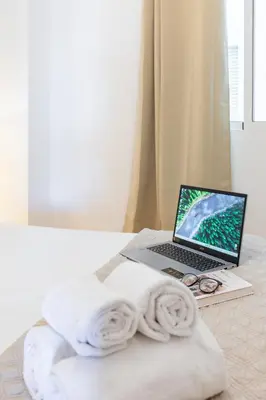 a laptop computer sitting on top of a bed with a towel at Travel Habitat Torres de Serrano in Valencia