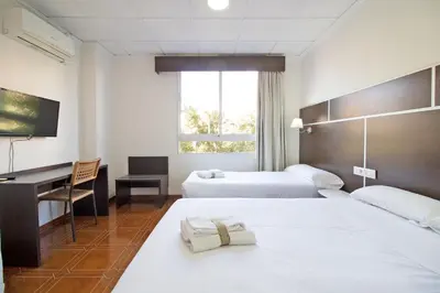 a hotel room with two beds and a desk at Hotel Sagunto in Sagunto