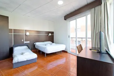a room with two beds and a flat screen tv at Hotel Sagunto in Sagunto