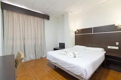 a hotel room with a large white bed and a window at Hotel Sagunto in Sagunto