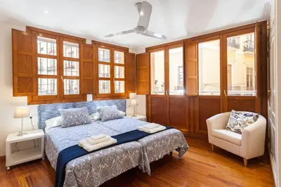 a bedroom with a bed and a chair and windows at Apartamento Torres in Valencia