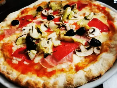 a pizza with toppings on a plate on a table at Hotel L'Escala in Cullera